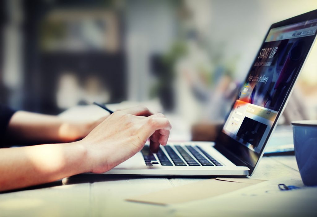 Profile view of woman's hands working on a laptop.