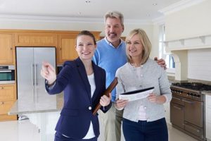 Female Realtor showing a mature couple a house from the kitchen.