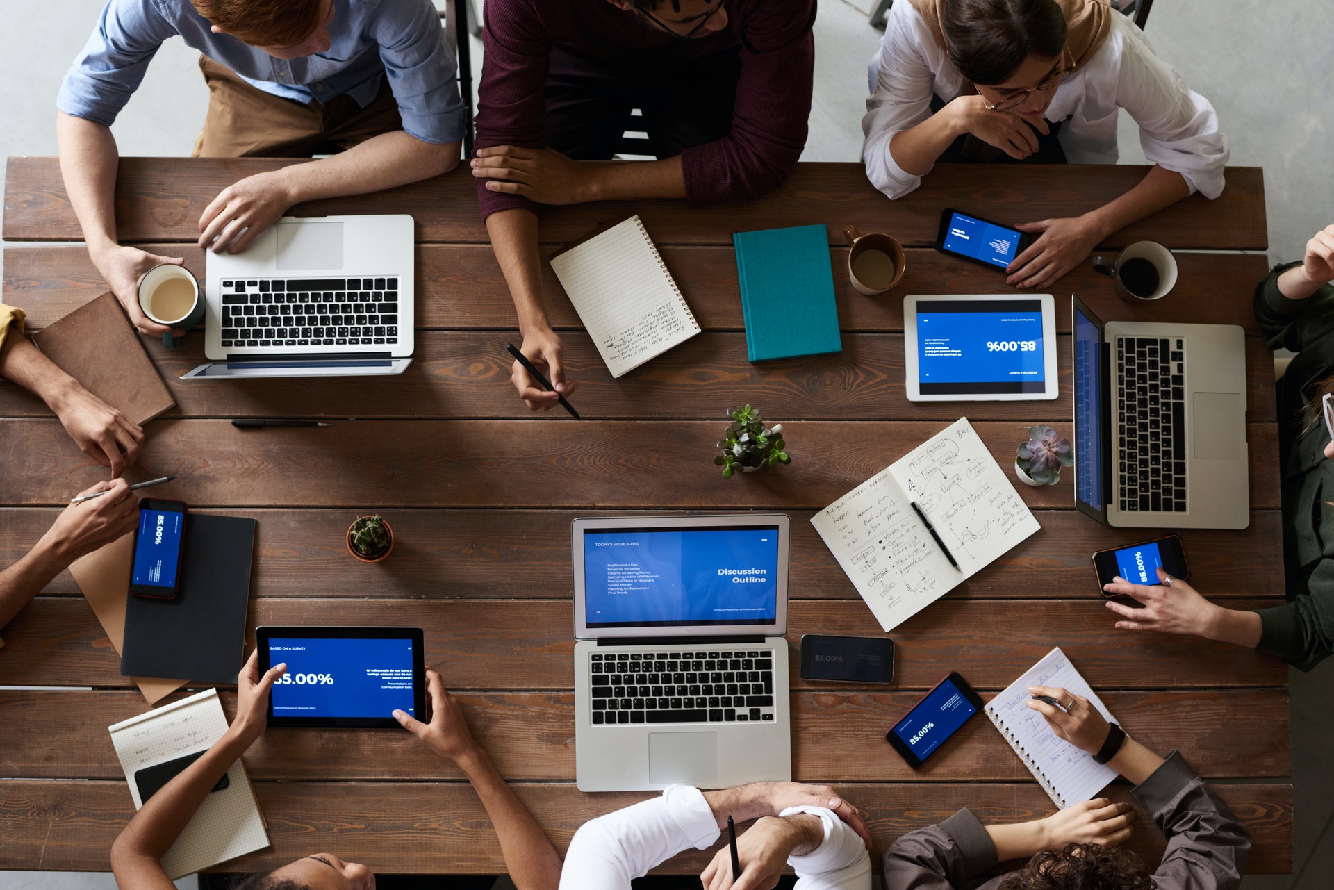 Overhead view of marketing team at a conference table working on a project with laptops and tablets.